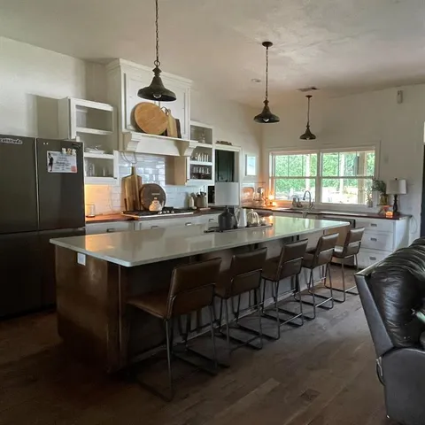 a kitchen with a dining table chairs sink and wooden floor