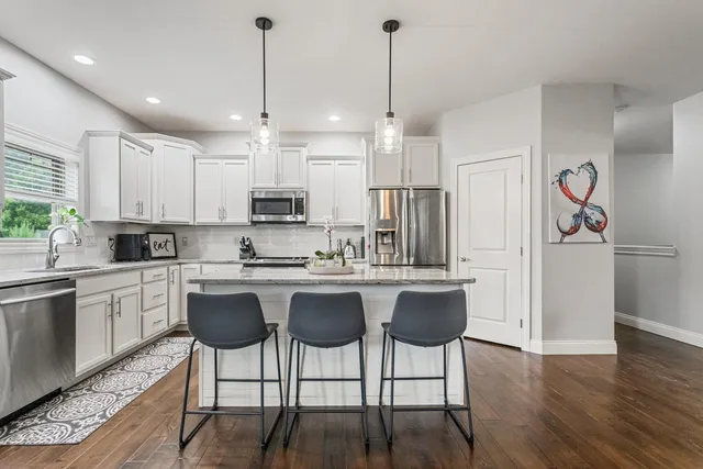 a kitchen with stainless steel appliances granite countertop a sink a stove a refrigerator and island with wooden floor