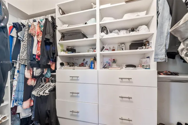 a view of walk in closet with clothes and shoes