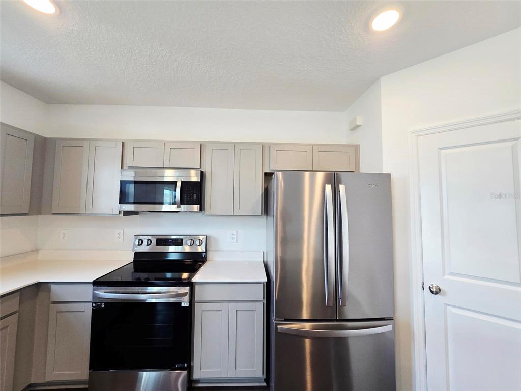 13031 Bluff Oak Way Parrish, FL 34219 - Photo 4 of 25 a kitchen with stainless steel appliances a refrigerator a stove and white cabinets