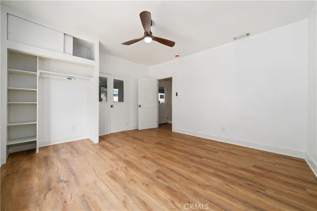 a view of empty room with wooden floor and ceiling fan