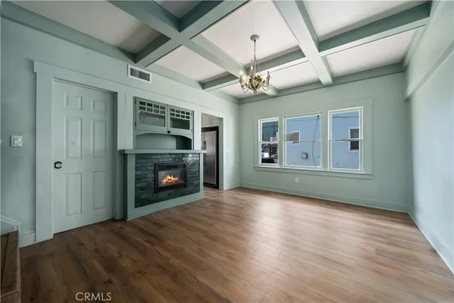 a view of an empty room with wooden floor fireplace and a window
