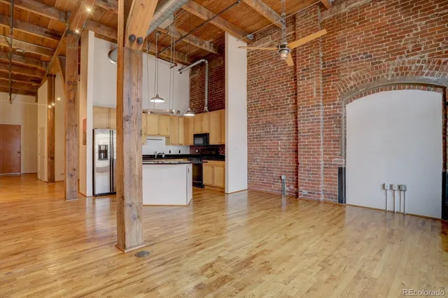 a view of empty room with wooden floor and kitchen