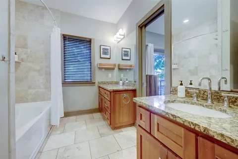 a bathroom with a granite countertop sink and a bathtub
