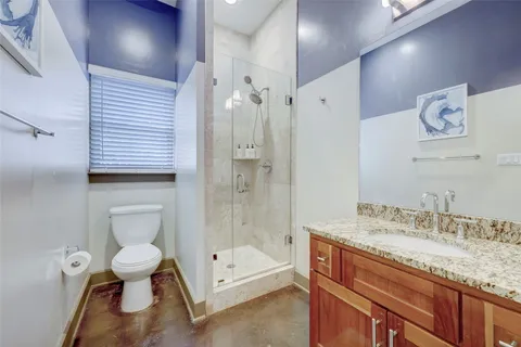 a bathroom with a granite countertop sink a toilet and shower