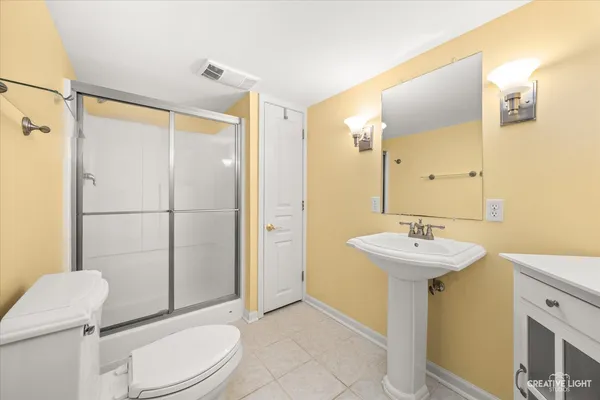 a bathroom with a sink a toilet a mirror and shower