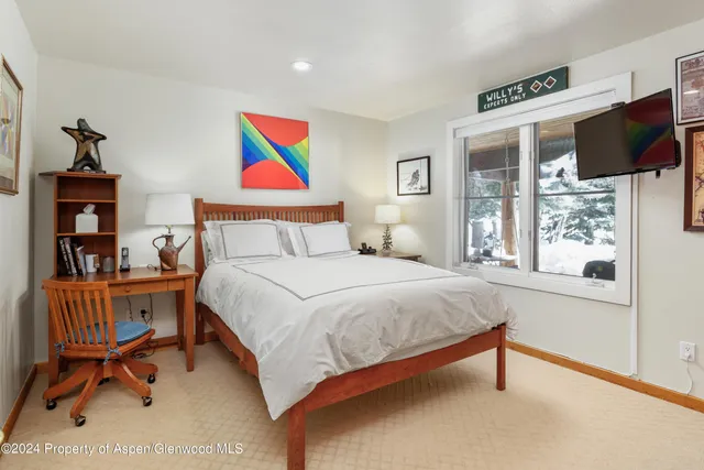 a bedroom with a bed and a flat tv screen next to a window