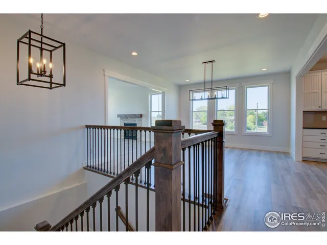 a view of a hallway to room with wooden floor and windows