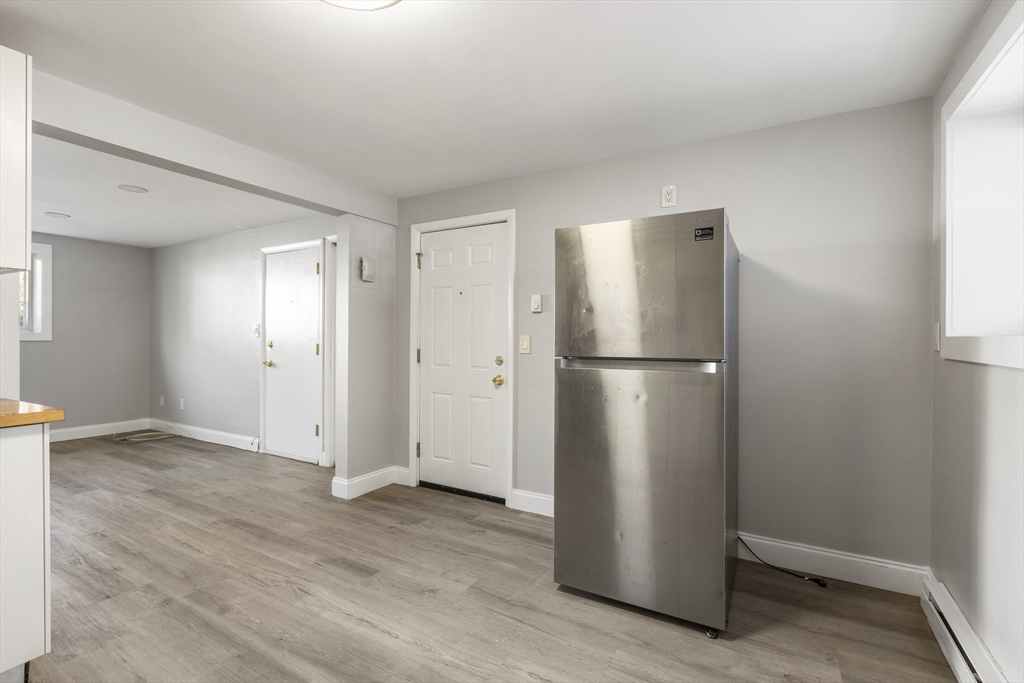 96 Itasca Street, Unit 961 Boston, MA 02126 - Photo 6 of 18 a view of an empty room with wooden floor and a kitchen