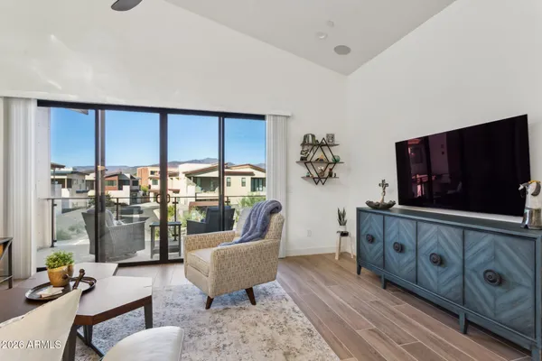 a living room with furniture a flat screen tv and floor to ceiling window