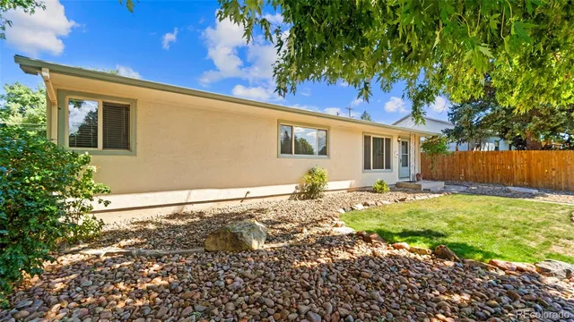 a backyard of a house with table and chairs under an umbrella
