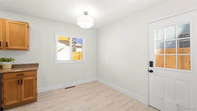 a view of an empty room with window and wooden floor