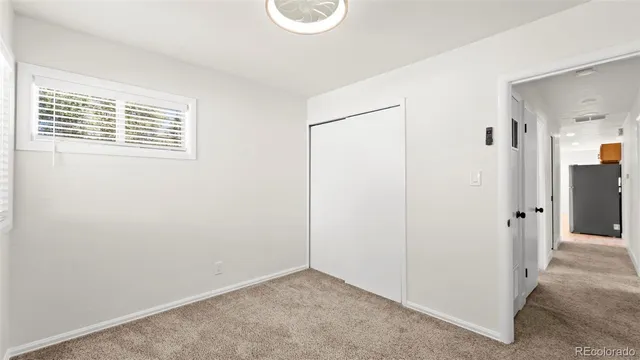 an empty room with a ceiling fan and carpet