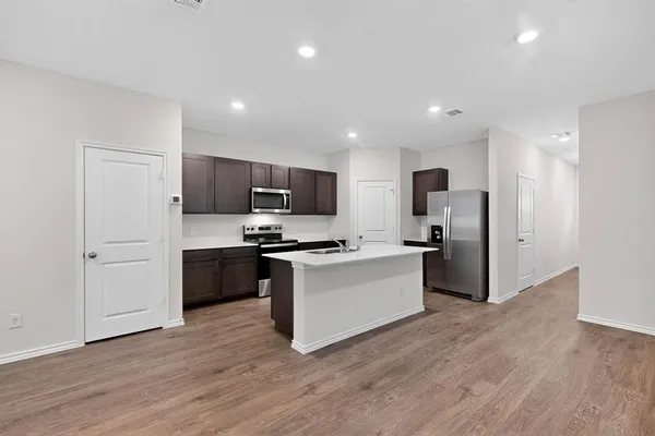 a kitchen with stainless steel appliances a refrigerator a stove top oven a sink and dishwasher with wooden floor