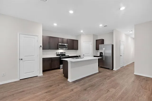 a kitchen with stainless steel appliances a refrigerator a stove top oven a sink and dishwasher with wooden floor