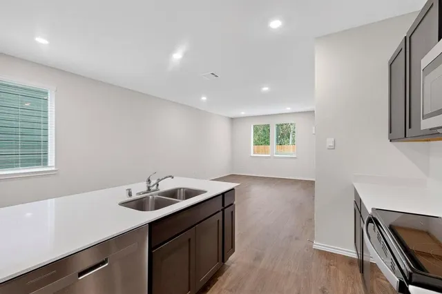 a kitchen with a sink dishwasher a stove and a refrigerator with wooden floor