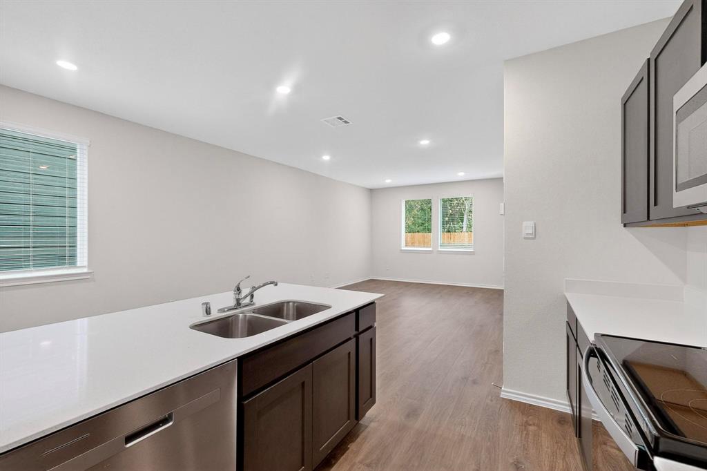 7008 Vining Drive Princeton, TX 75407 - Photo 9 of 34 a kitchen with a sink dishwasher a stove and a refrigerator with wooden floor