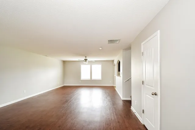 an empty room with wooden floor and windows