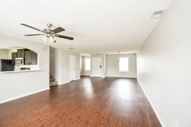 a view of an empty room with window and wooden floor