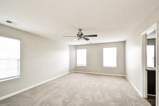 an empty room with windows and fan