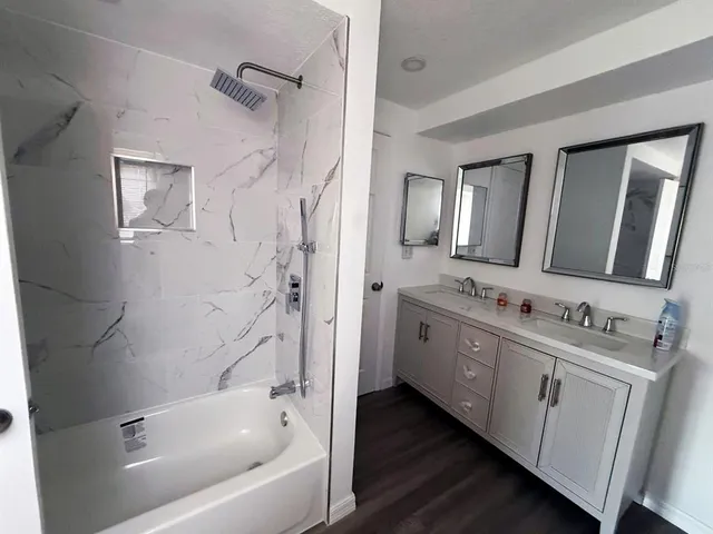 a bathroom with a tub sink double vanity and a mirror