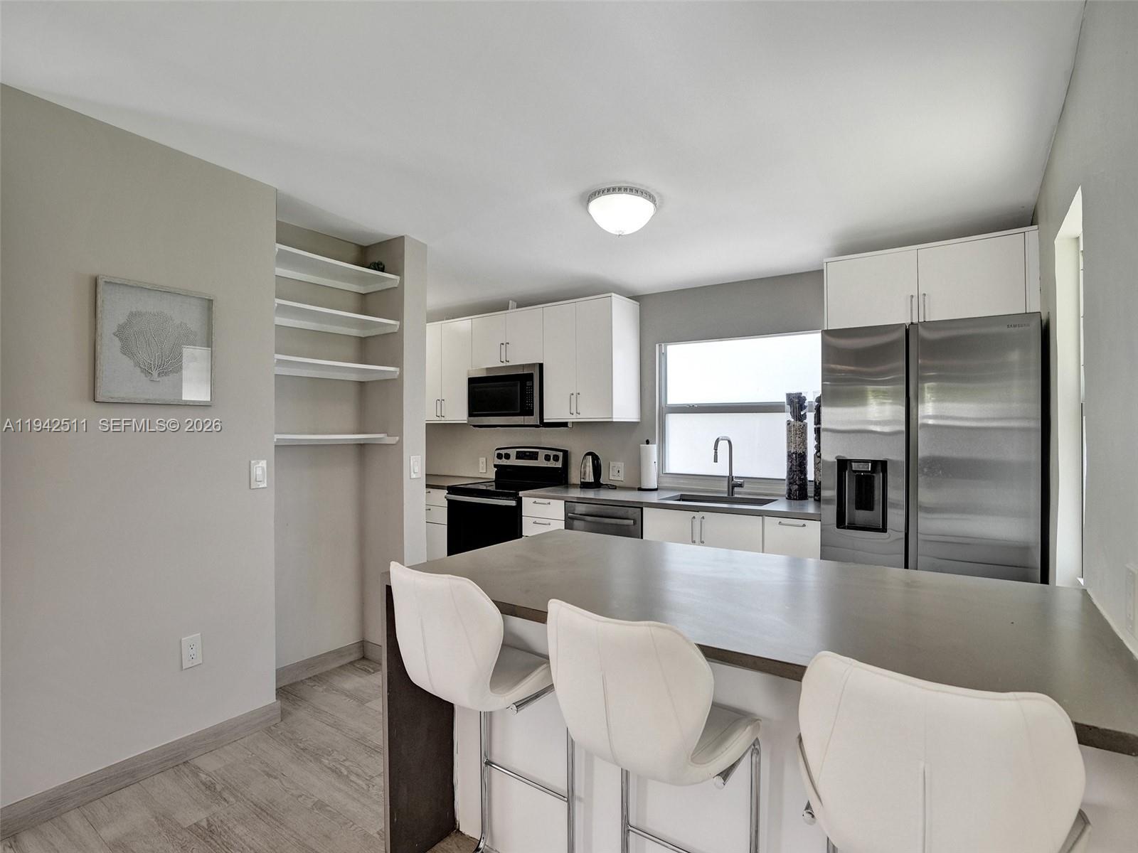 1128 Tyler Street Hollywood, FL 33019 - Photo 44 of 60 a kitchen with stainless steel appliances granite countertop a refrigerator a stove top oven a sink dishwasher and white cabinets with wooden floor