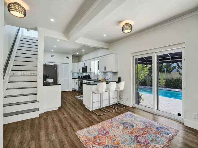 a kitchen with stainless steel appliances granite countertop a sink dishwasher a refrigerator and white cabinets with wooden floor