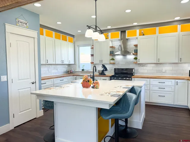 a kitchen with a stove a sink and white cabinets with wooden floor