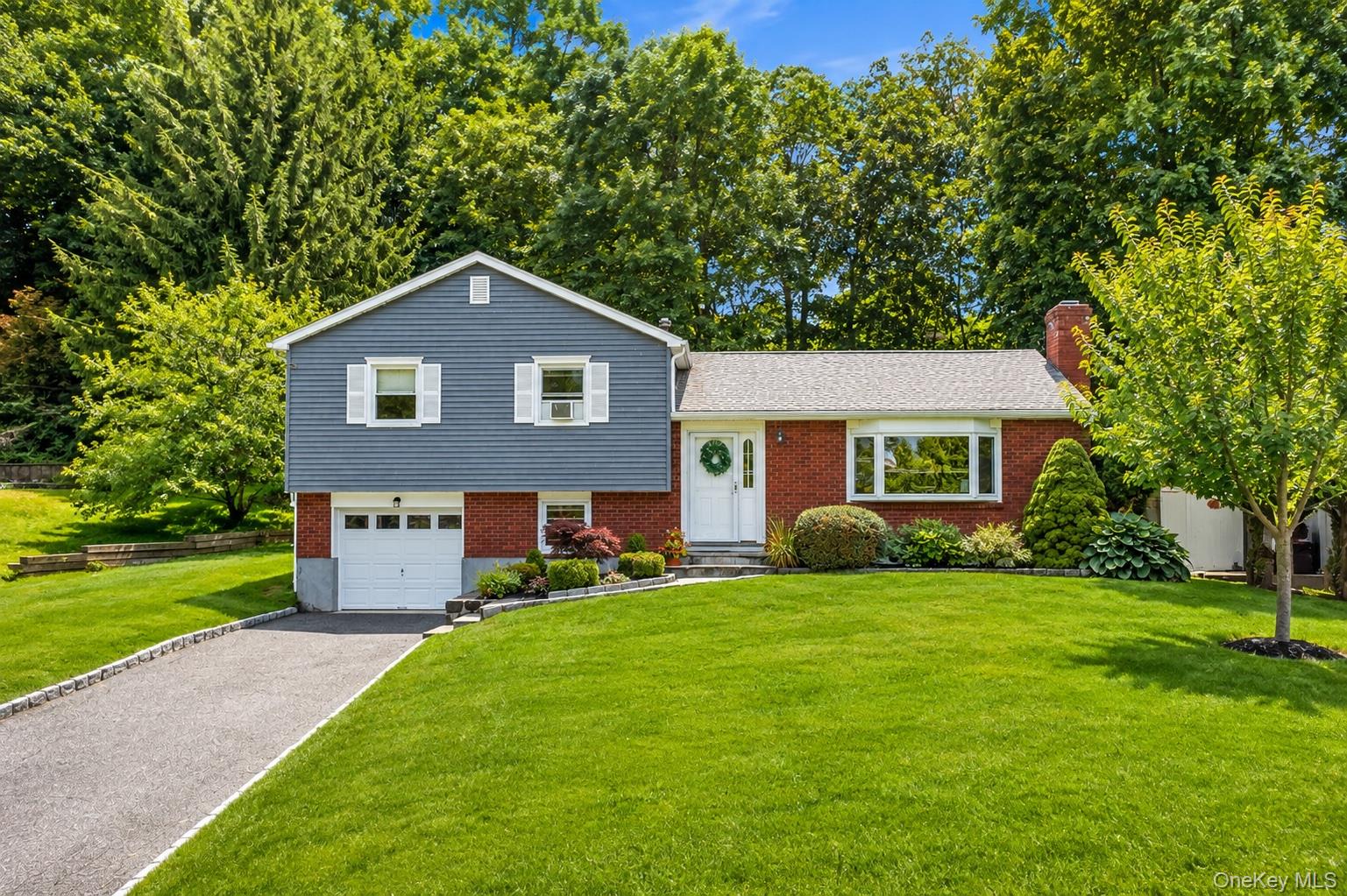 617 Cardinal Road Cortlandt Manor, NY 10567 - Photo 1 of 32 Split-level residence featuring a brick and blue siding exterior, an attached single-car garage, and a paved driveway