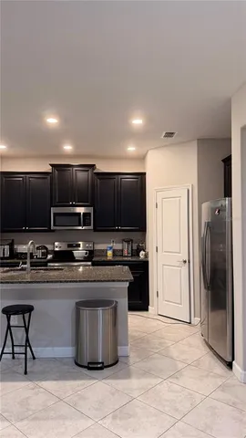a kitchen with stainless steel appliances granite countertop a stove top oven a sink and a refrigerator