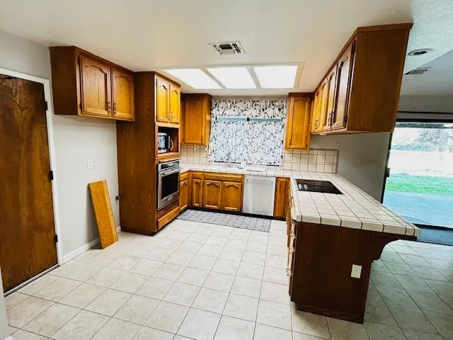 a kitchen with stainless steel appliances granite countertop a refrigerator a stove and a sink