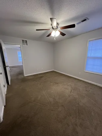 an empty room with windows and fan