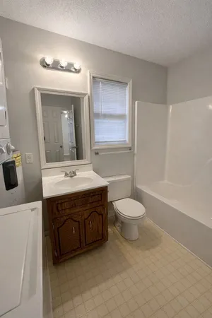 a bathroom with a toilet a sink a tub and mirror