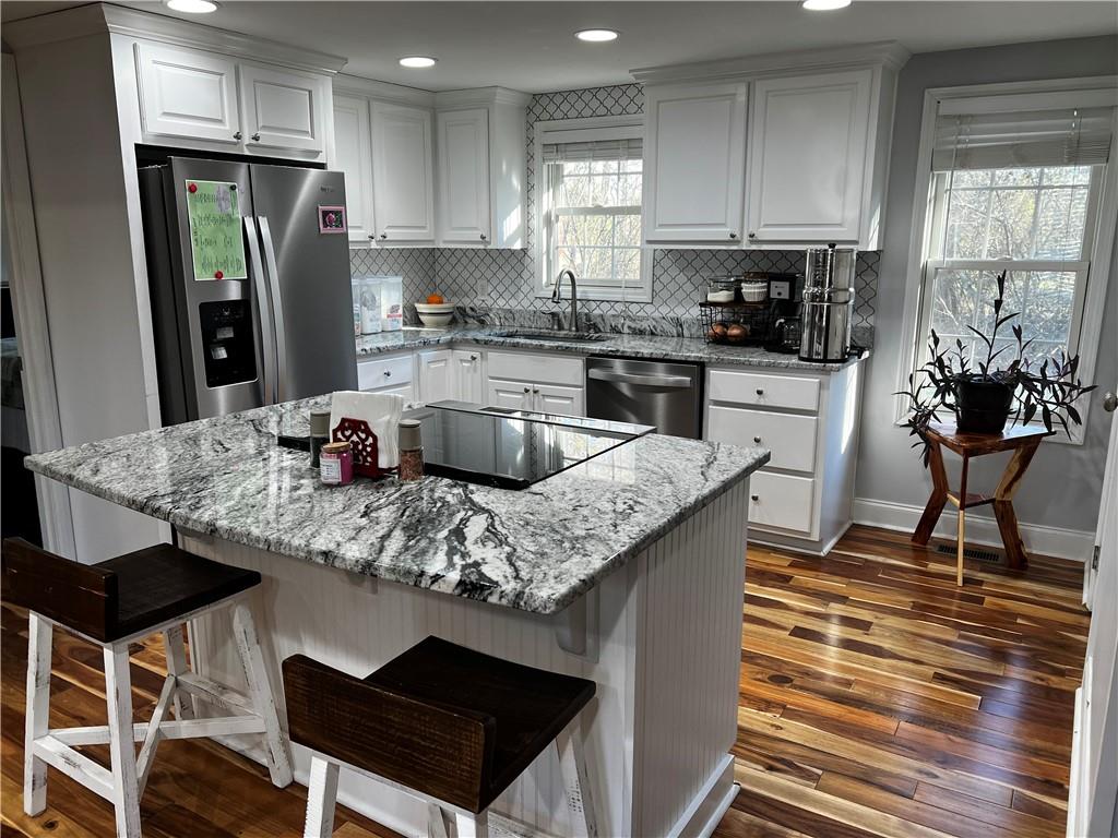 a kitchen with stainless steel appliances granite countertop a kitchen island hardwood floor sink and stove