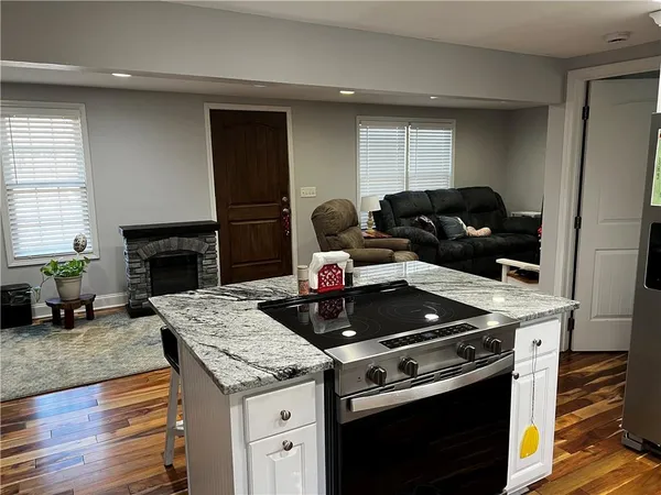 a kitchen with granite countertop a stove and a wooden floors