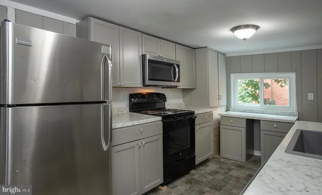 a kitchen with stainless steel appliances granite countertop a refrigerator a stove a sink and a microwave