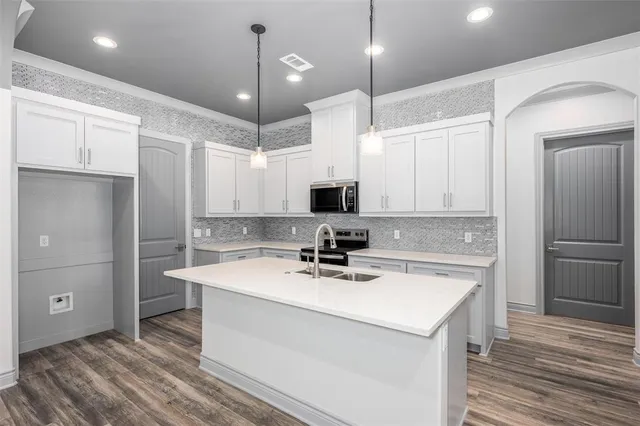 a kitchen with a sink a center island stainless steel appliances and cabinets