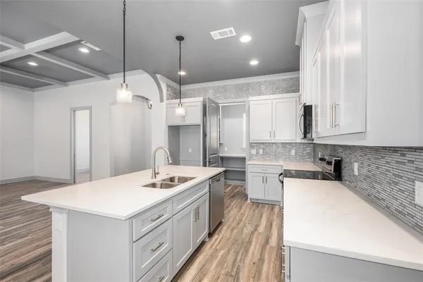 a kitchen with a sink a counter space appliances and cabinets
