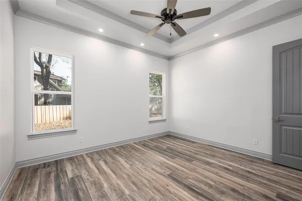 a view of empty room with wooden floor and fan