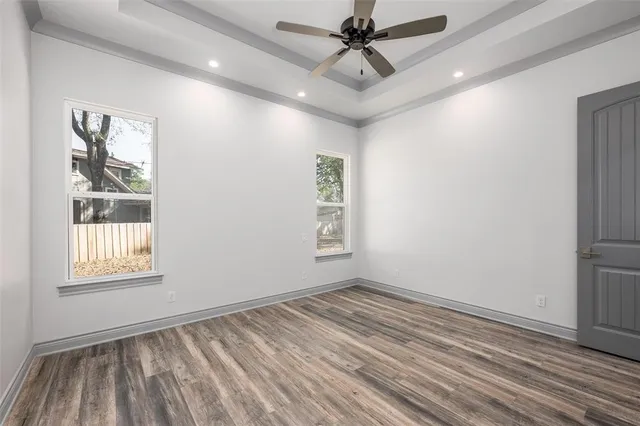 a view of empty room with wooden floor and fan