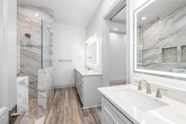 a bathroom with a sink a toilet a mirror and shower