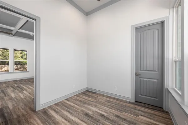 an empty room with wooden floor closet and windows