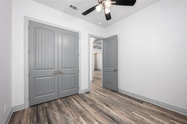 an empty room with a hardwood and ceiling fan