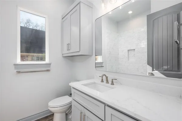 a bathroom with a granite countertop sink a toilet and a mirror