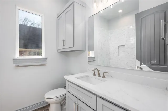 a bathroom with a granite countertop sink a toilet and a mirror