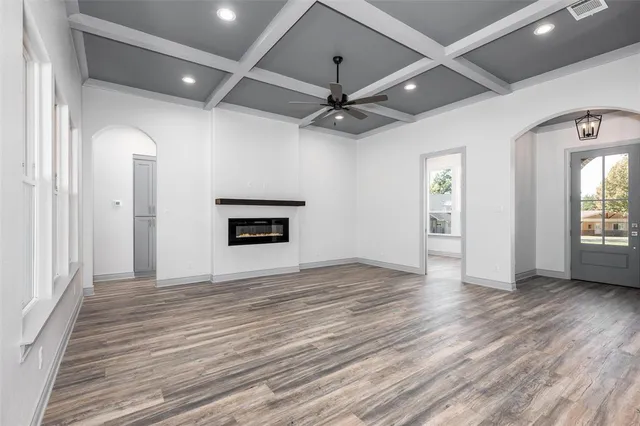 an empty room with wooden floor ceiling fan and windows