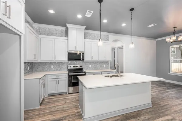 a kitchen with a sink a stove a refrigerator and white cabinets