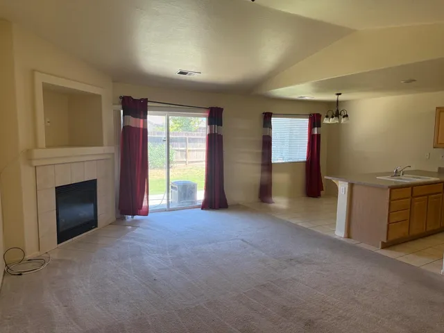 a view of an empty room with a fireplace and a window