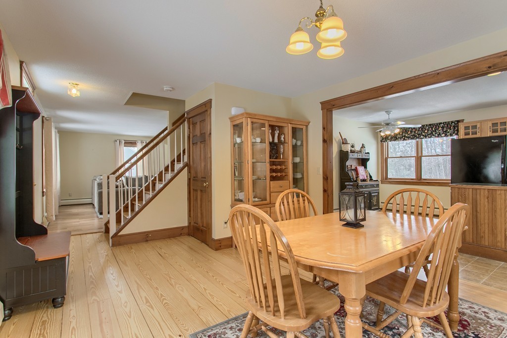 253 New Boston Road Sturbridge, MA 01566 - Photo 3 of 30 a dining room with wooden floor a chandelier a wooden table and chairs