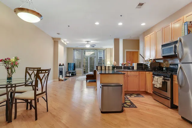 a kitchen with stainless steel appliances granite countertop a stove top oven a sink a dining table and chairs